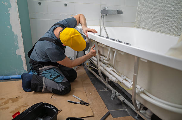 Symbolbild: Handwerker arbeitet an den Rohrleitungen einer Badewanne.